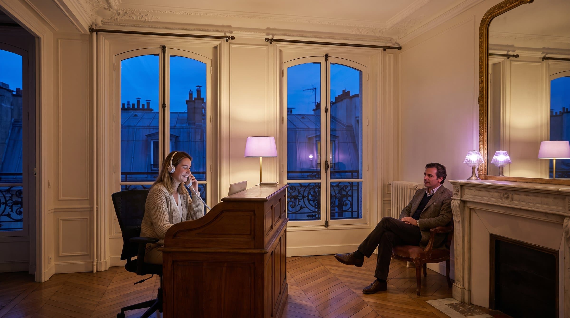 Réceptionniste avec un casque au téléphone à l’accueil d’un cabinet dentaire dans un appartement haussmannien à Paris, à l’heure bleue